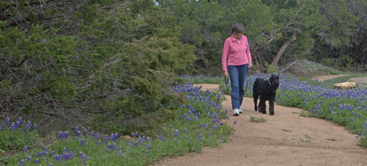 Woman walking her dog on a trail.