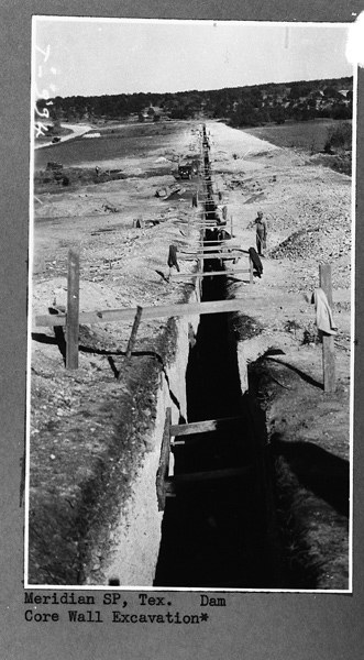 Historical photo of the dam under construction. Says, "Meridian SP, Tex Dam. Core Wall Excavation*"