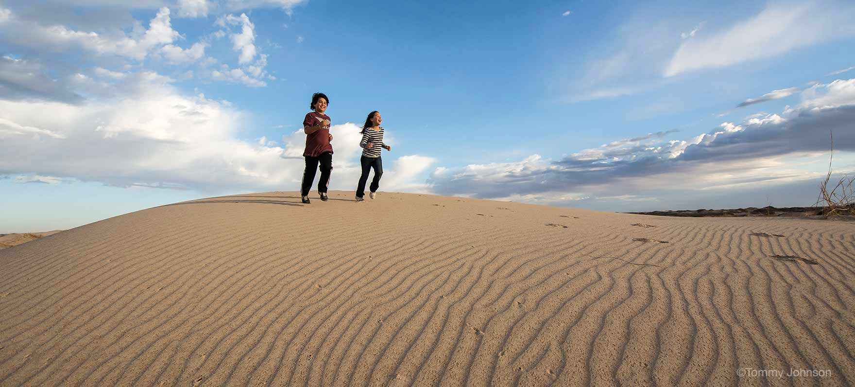 mother and daughter running down sand dune