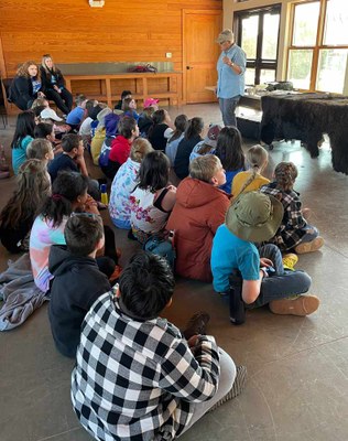Students sit on the floor listening to a presenter