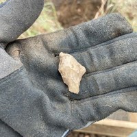 Gloved hand holding an arrowhead