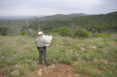 Park employee holding map looking out over park lands