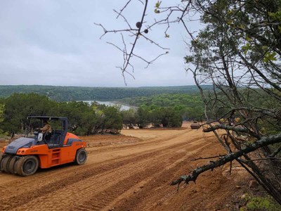 Road crew smoothing dirt for road to boat ramp. The lake is in the distance.