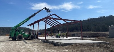 Metal building frame on a slab with workers standing underneath