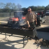 Man in park uniform stands over a barbecue grill