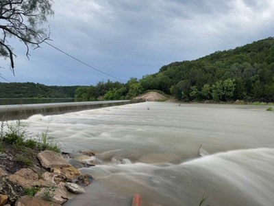 Water flowing over a dam underneath dark clouds