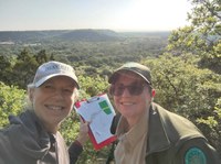Two women gring at camera with view of park land behind them.