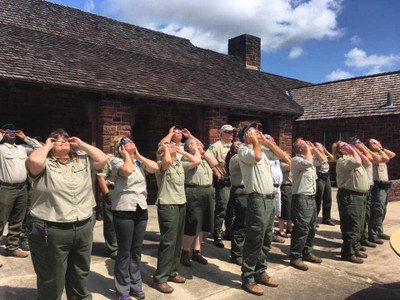 Park rangers stare up at the sky using solar viewing glasses.