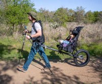 Man on a trail pulling a child in a hiking cart