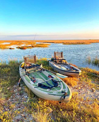 Two fishing kayaks pulled up on the shore.