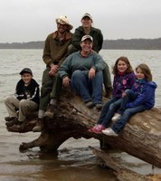 Family sitting on log at lake's edge