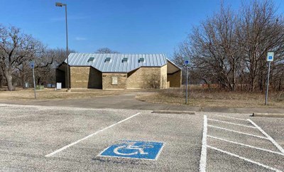 tan brick building with sidewalk from parking area