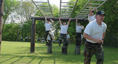 Numerous cadets on monkey bars of obstacle course